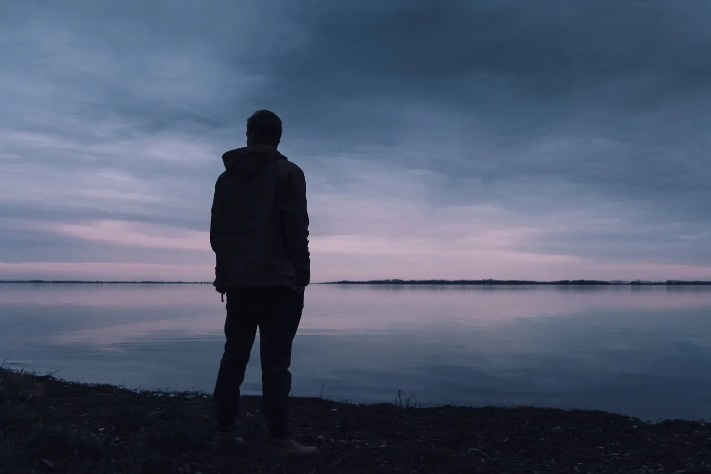A man standing alone on a beach at sunset, symbolising reflection and healing through borderline personality disorder therapy.